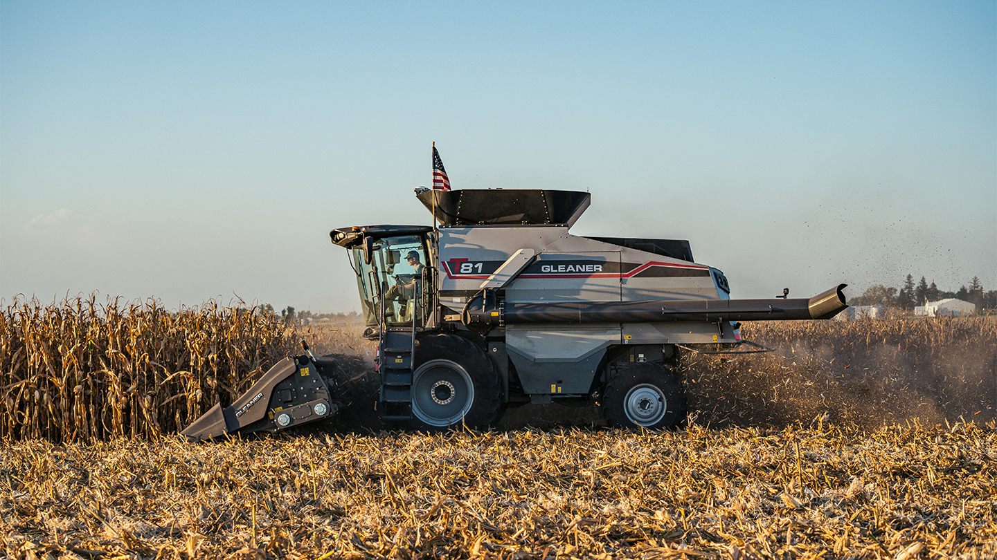 Gleaner T Series combine harvesting corn under a pale blue sky.